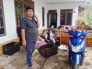Foto H Holil saat di datangi pembeli tomat dan semangka